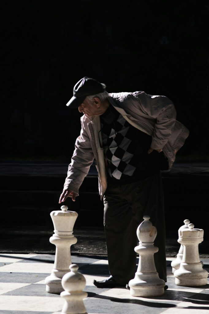 Elderly white man playing large life-size chess.